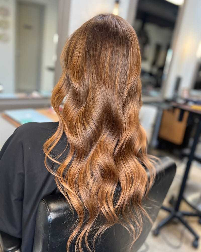 Long wavy auburn hair styled in a salon setting.
