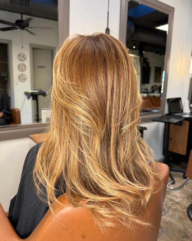 Woman with layered, shoulder-length blonde hair in a salon chair.