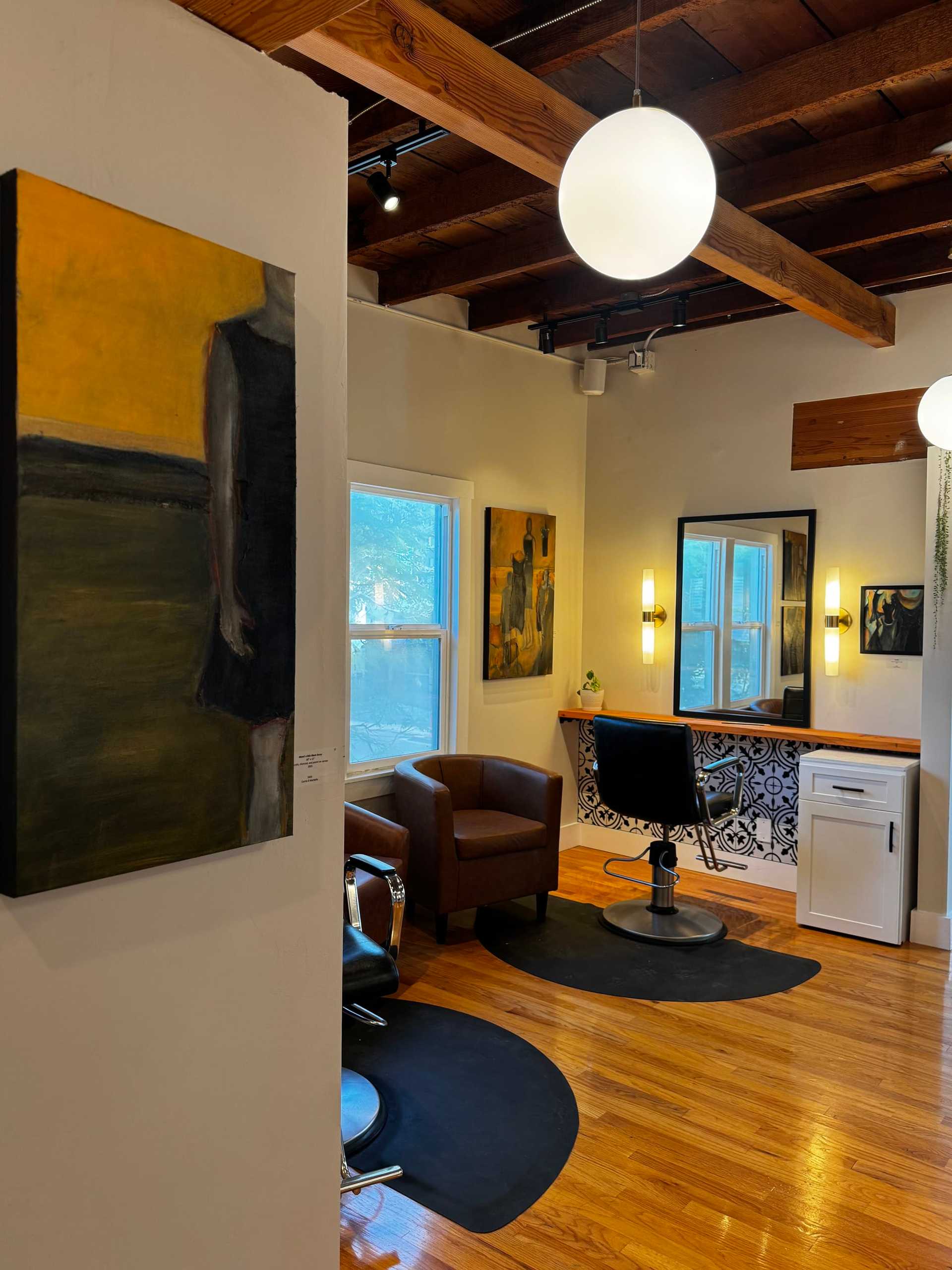 Cozy salon interior with art on walls, wooden ceiling, and stylish seating.