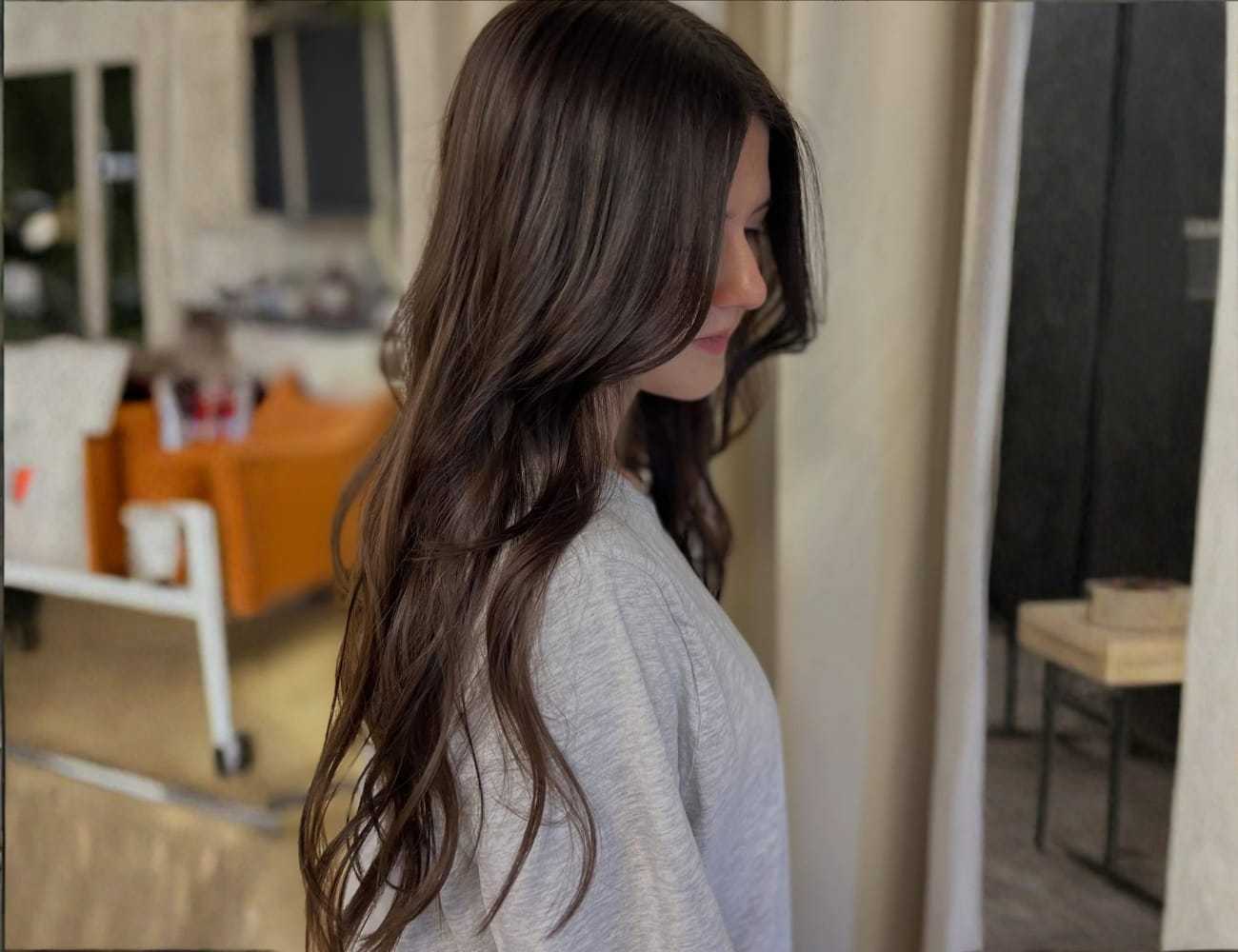 Woman with long brown hair in a side profile view indoors.