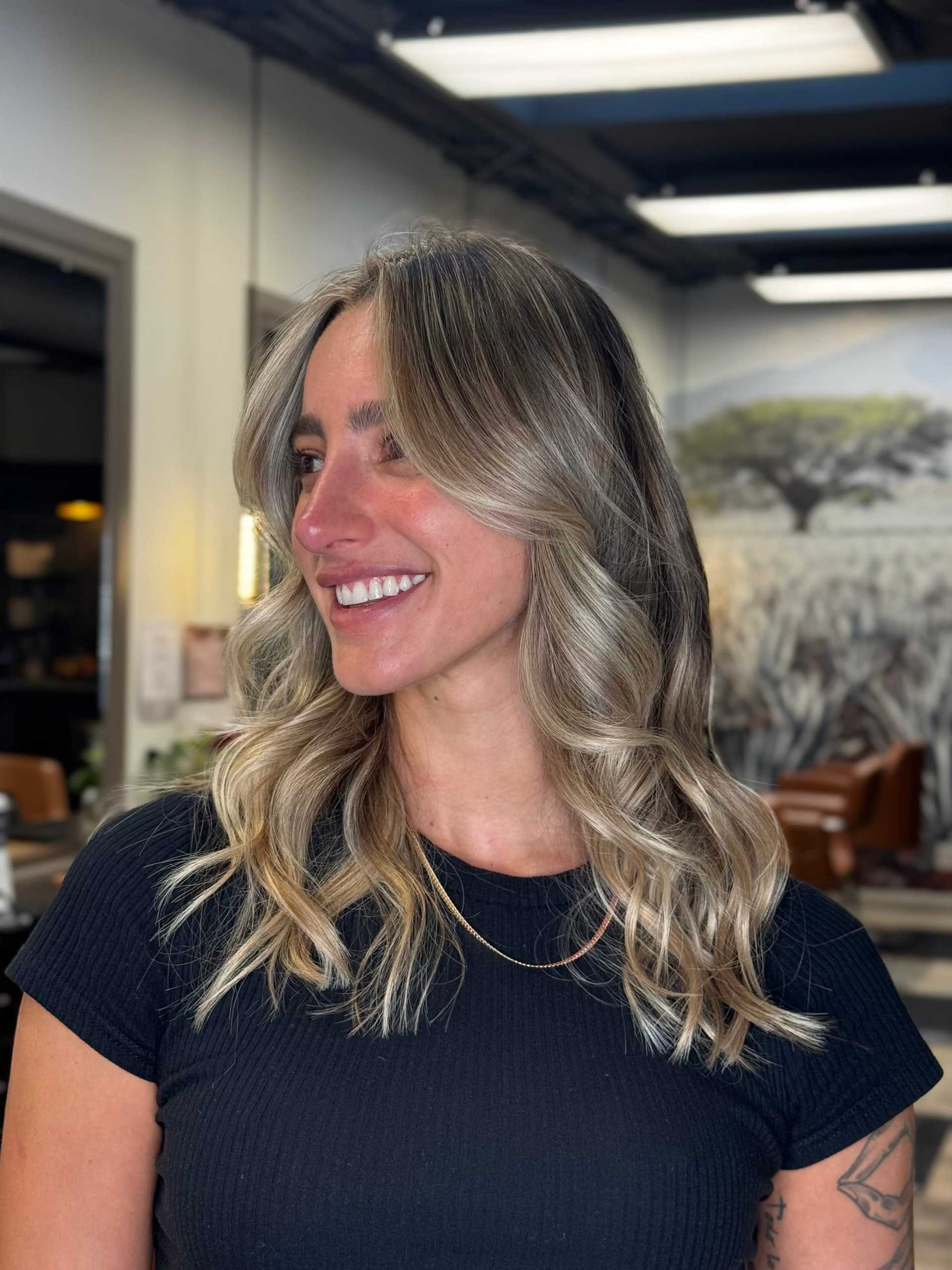 Smiling woman with wavy blonde hair in a salon setting.