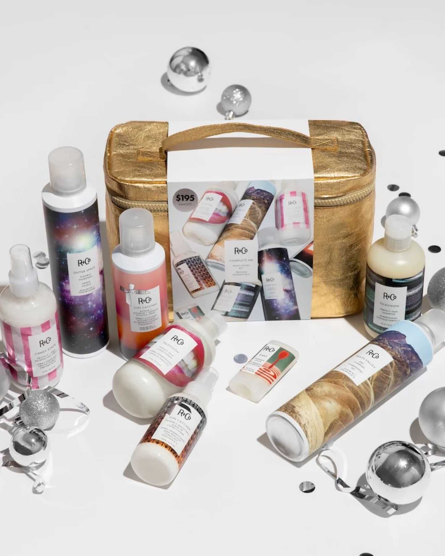 Gold bag with various R+Co hair products and festive decorations.