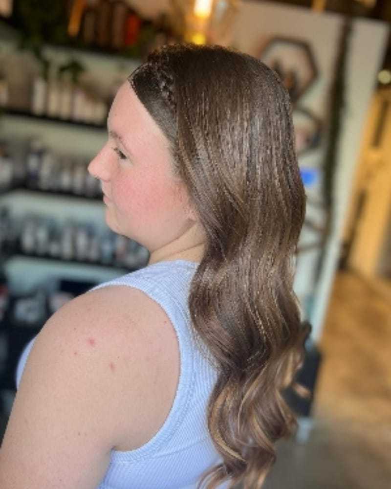Woman with long, wavy brown hair in a salon setting.